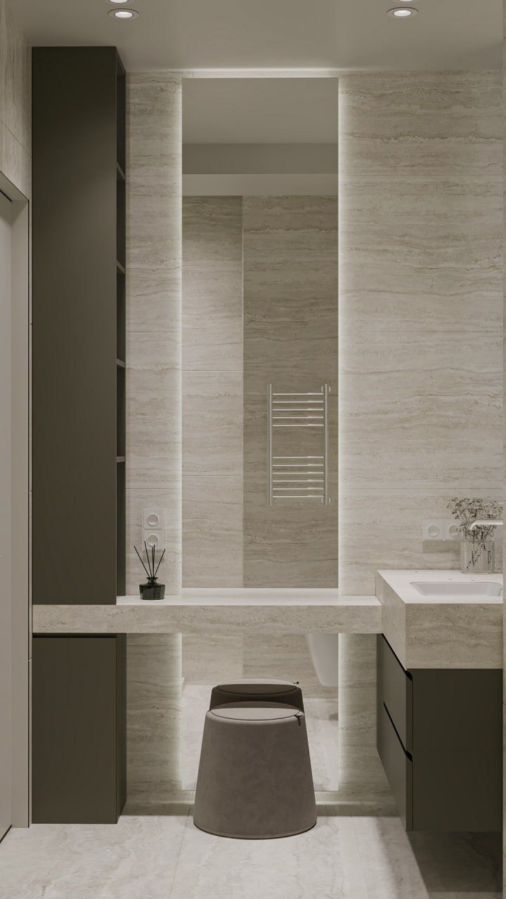 Bathroom — travertine walls, a long stone counter with a stool, dark cabinets and a tall backlit mirror.