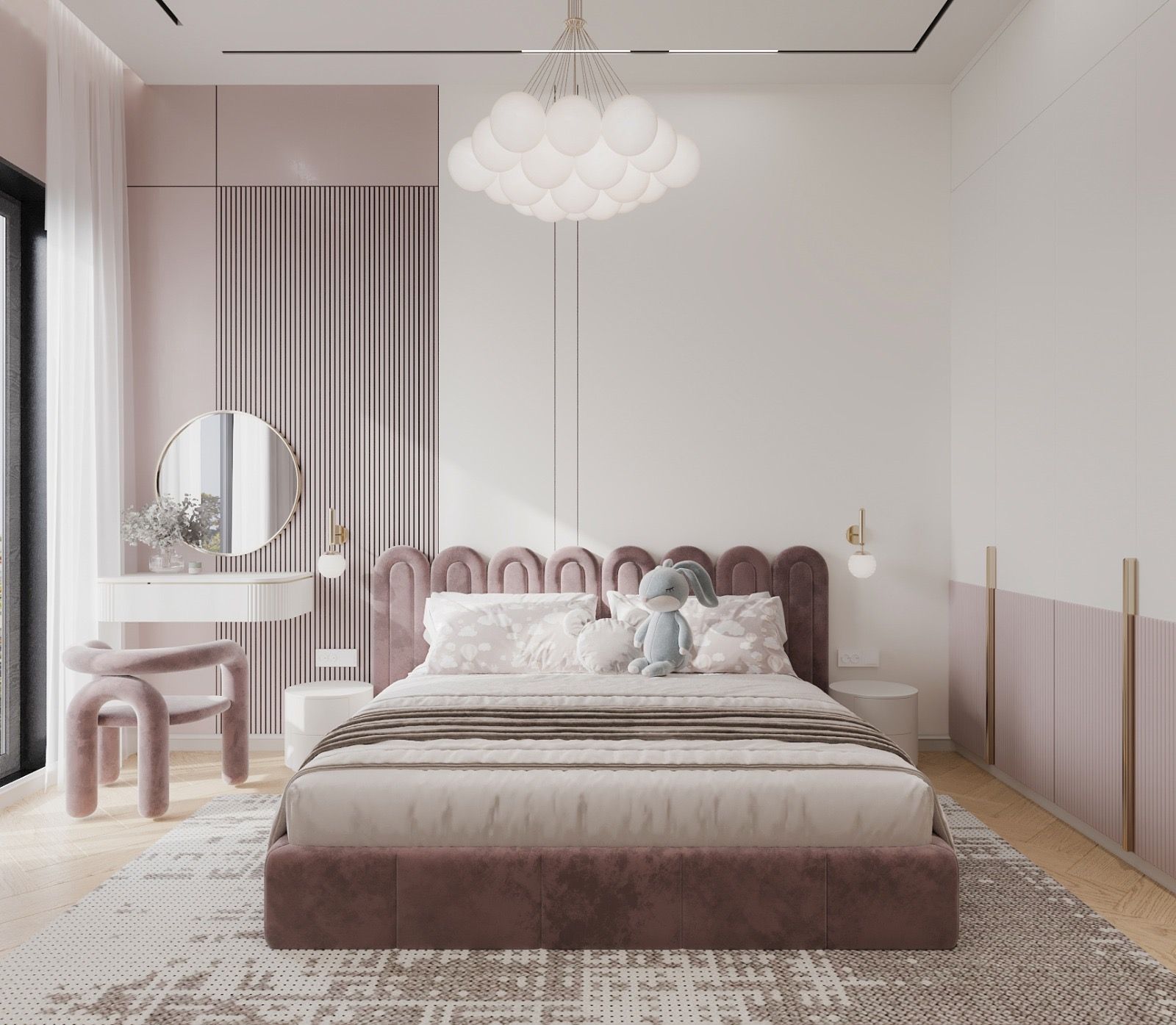 Bedroom in rose — an arched, upholstered headboard, a cluster pendant of white globes, a round mirror over a floating dressing table and a soft curved chair.
